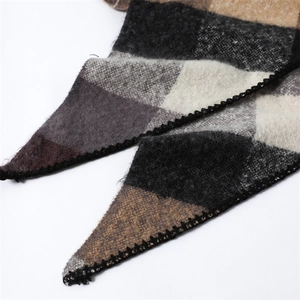 Macro view of checkered wool scarf texture with black stitching and soft fringe edges