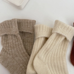 Detail of chunky knit wool crew socks in beige and oatmeal with ribbed cuffs
