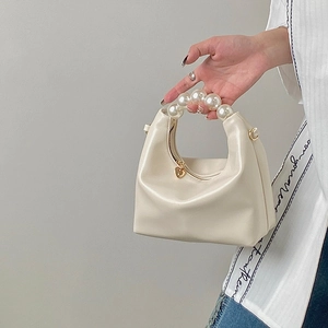 Detail of white soft faux leather bag with pearl handle and golden heart-shaped zipper