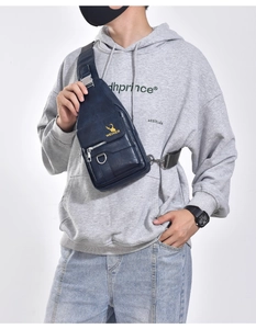 Detail of blue leather chest bag with golden deer logo and adjustable crossbody strap
