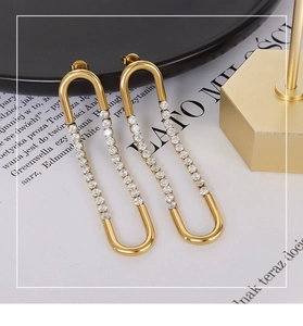 Detail showing gold U-shaped earrings with sparkling cubic zirconia on white paper