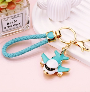 Macro view of a blue airplane keychain with braided rope on a pink and white surface