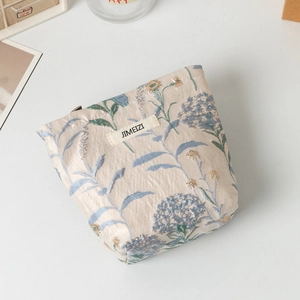 Dettaglio della trama jacquard floreale e della cerniera sulla borsa cosmetica color panna