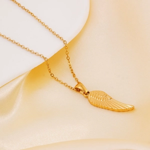 Close-up of golden wing pendant necklace on elegant beige silk and white display