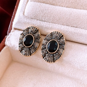 Macro shot of vintage oval earrings with black gemstones and crystals in a velvet box