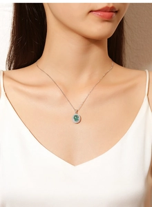 Macro detail of S925 silver necklace featuring an oval green emerald pendant on a model