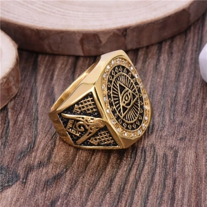 Vintage gold Freemason ring with All-Seeing Eye and compass symbols on wood background