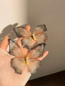 Detail of sheer mesh butterfly hair clips featuring gradient colors and pearl accents