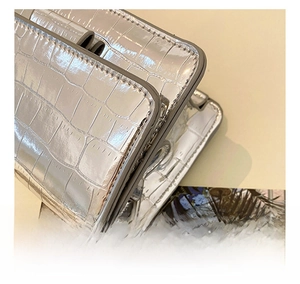 Close-up of silver crocodile embossed texture and precision stitching on mini crossbody bag