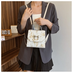Lifestyle shot of a white backpack featuring gold butterfly prints and a silver bow clasp