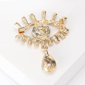 Back view of gold evil eye brooch with blue diamond and teardrop pendant details