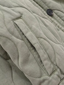 Détail de la veste en coton matelassé vert sauge avec bouton et poche latérale