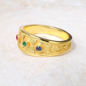 Detailed macro view of vintage gold ring with red, green, and blue zircon stones