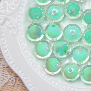 Macro detail of iridescent light green round beads with core holes on a ceramic plate
