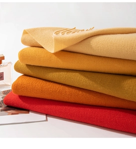 Close-up of warm-toned cashmere feel scarves in beige, yellow, and red with soft texture