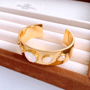 Detail view of gold-plated open cuff bracelet featuring moonstone cabochon settings