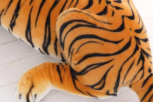 Detailed macro view of soft orange and black striped plush faux fur fabric on a tiger doll