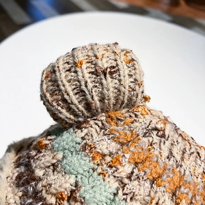 Macro detail of multi-colored knit texture and thick wool ball on the festive beanie