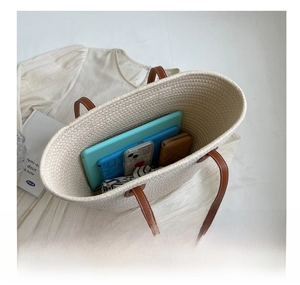 Macro shot of large capacity beige woven tote bag interior with brown leather handles