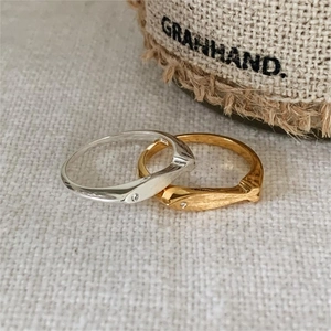 Close-up of gold and silver brushed fish rings with zircon eyes on woven fabric