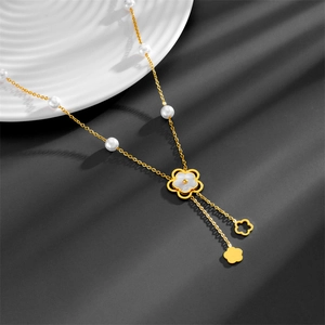 Elegant gold pearl necklace with camellia shell pendant draped on a white plate