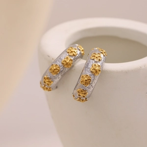 Macro shot of two-tone flower engraved C-shaped earrings in stainless steel