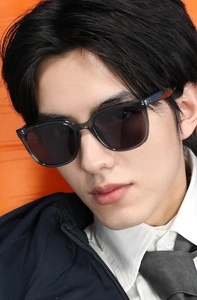 Close-up of modern square polarized sunglasses with gray translucent frames on a male model