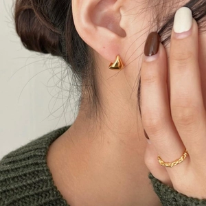 Minimalist gold triangle hoop earrings and textured chain ring on a female model
