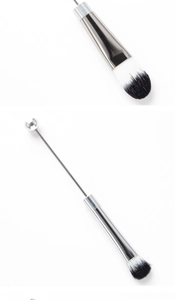 Detailed macro view of a dual-ended makeup brush with silver handle and metallic ball tip