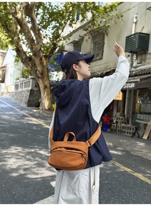 Outdoor street shot of a model wearing a caramel nylon crossbody chest bag with wide strap