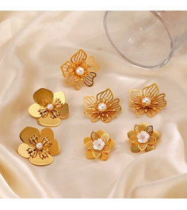 Detail of oversized gold flower earrings with white pearl centers on champagne satin