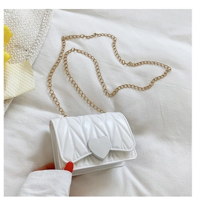Detailed shot of mini white heart crossbody bag with gold chain and quilted texture