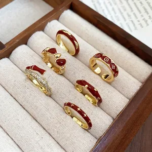 Vintage 14k gold plated rings with red enamel patterns in a wooden jewelry box