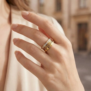 Close-up of golden multi-layer ring with Roman numeral engraving and crystal setting