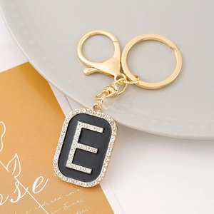 Detail of a gold rhinestone letter E keychain with black rectangle pendant on card