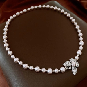 Détail du collier de perles avec pendentif papillon en zircon sur fond de soie
