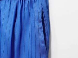 Detail of blue striped pants featuring an elastic pleated waist and side pockets