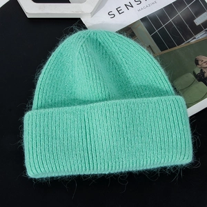 Detailed close-up of mint green faux fur knit beanie with thick ribbed texture