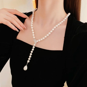 Detail of Y-shaped pearl necklace featuring a zircon leaf and large pear-shaped pearl pendant