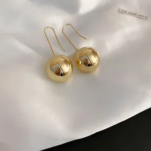 Elegant gold spherical bead earrings with long hooks on white silk background