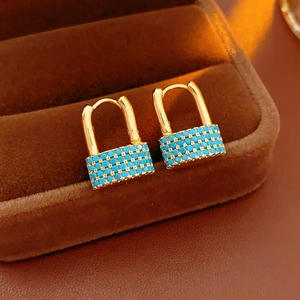 Macro shot of gold lock earrings with turquoise beads in a luxury brown velvet case