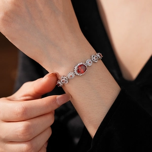 Detailed close-up of a silver bracelet featuring oval red gemstone and white zircon stones