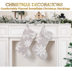 Detail of plush grey Christmas stockings with white snowflake patterns on a fireplace