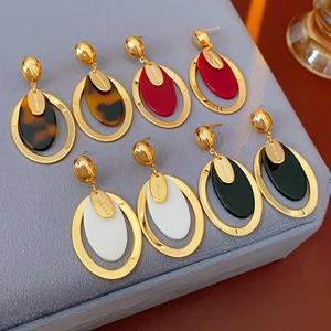 Detail of oval resin earrings in gold plating featuring handmade tortoise and white colors
