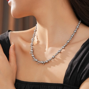 Detailed view of grey pearl necklace with silver star charms on a female neck