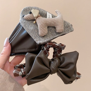 Close-up of brown acrylic claw clip with fabric puppy charm and faux leather bow scrunchie