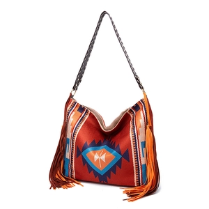 Detail of bohemian woven hobo bag featuring geometric patterns and long side fringes