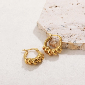 Macro shot of gold-plated twisted hoop earrings on a natural stone display