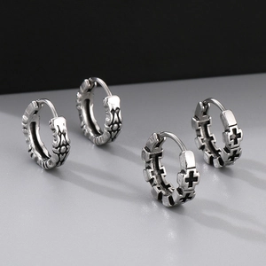 Detailed view of vintage silver earrings featuring gothic cross reliefs and textures