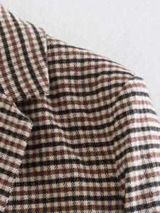 Nahaufnahme des braunen Hahnentritt-Wollmischgewebes an einem schicken Blazer-Revers